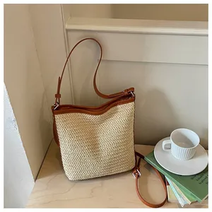 Bolso de paja tejida informal con correas de cuero marrón en un ambiente acogedor