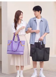 Modische männliche und weibliche Models tragen große lila und schwarze Reisetaschen.