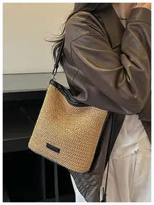 Detalle de un bolso bandolera minimalista de paja tejida con una chaqueta de cuero