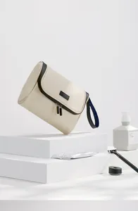 Κοντινό πλάνο μπεζ τσάντας νεσεσέρ ταξιδιού σε λευκές πλατφόρμες
