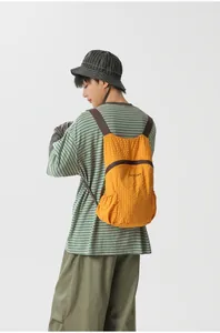 Lightweight orange foldable backpack shown on an Asian model for outdoor hiking and travel