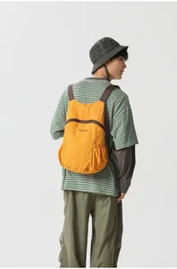 Back view of a yellow foldable lightweight travel backpack worn by a male model