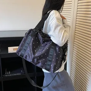 Side view of a large capacity polka dot travel bag with black straps carried by a model