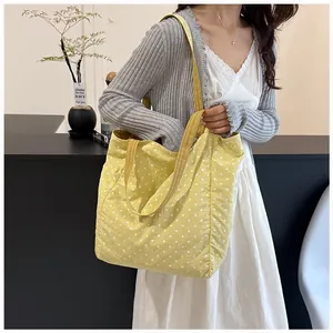 Yellow polka dot canvas tote bag carried by a model in a stylish lifestyle setting