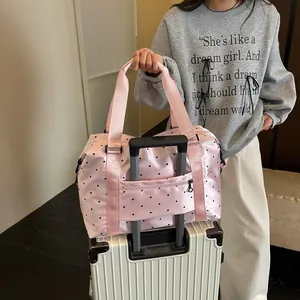 Close-up detail of a pink polka dot travel bag featuring a convenient luggage trolley sleeve