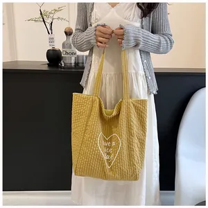 Yellow checkered canvas tote bag with a white heart print held by a model at home