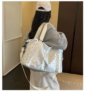 Rear view of a person carrying a large white polka-dot travel bag over the shoulder