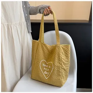 Detail of a yellow checkered tote bag with a white heart and nice day message