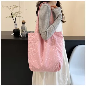 Pink polka dot canvas tote bag shown on a model for a stylish and versatile casual look