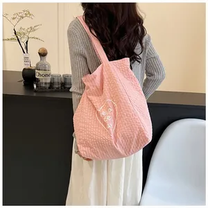Stylish pink canvas tote bag with heart print shown being worn by a model in detail view