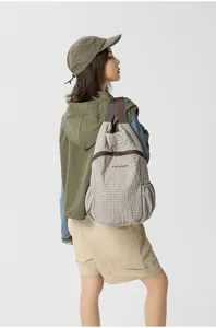 Detail of a lightweight foldable outdoor backpack worn by a female model in green hoodie.