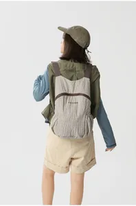 Back view of a woman wearing an ultralight foldable outdoor backpack with grey plaid pattern.