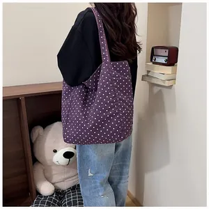 Lifestyle view of the purple polka dot canvas tote bag worn by a person in a room scene.