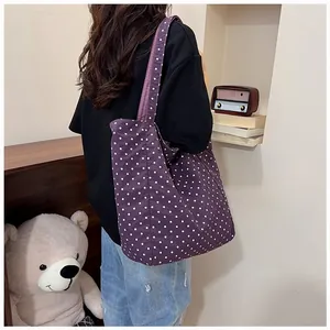 Purple polka dot canvas tote bag shown being worn by a model in a cozy indoor setting