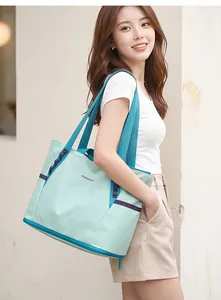 Detailansicht der mintgrünen Reisetasche mit blauen Trägern an einem Modell gezeigt.