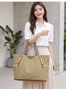 Asiatisches Model mit olivgrüner Reisetasche mit großem Fassungsvermögen in lässiger Umgebung