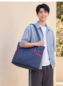 Asiatisches männliches Model mit großer blau karierter erweiterbarer Reisetasche im Freien