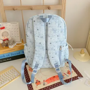 Rear view of light blue star print backpack showing padded straps and zipper pocket.