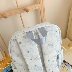 Detailed close-up of the light blue backpack featuring star patterns and sturdy top handle