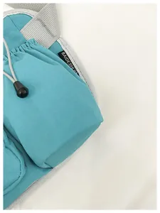 Close-up of teal crossbody bag detail with drawstring pocket and grid texture
