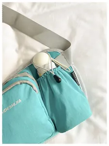 Detail view of mint green crossbody bag with a functional side drawstring pocket