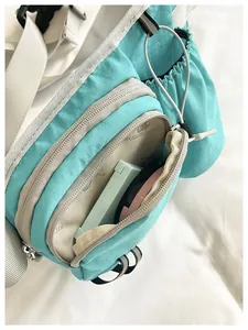 Detailed view showing the interior storage compartments of a turquoise nylon crossbody bag for women