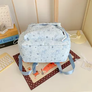 Close-up detail of a light blue star pattern backpack for girls in a cozy desk setting