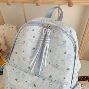 Close-up of a light blue star-patterned backpack featuring decorative rope zipper pulls