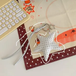 Close-up of a white polka dot star keychain charm with a silver cord and star ring