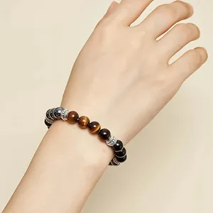 Detail view of natural tiger eye and black stone bracelet worn on wrist