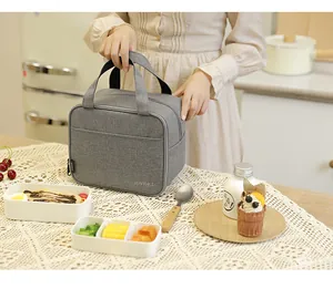 Borsa termica grigia per il pranzo con vari contenitori su tovaglia di pizzo