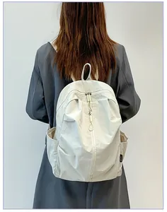 Vue détaillée d'un grand sac à dos en nylon blanc crème porté sur le dos du modèle.