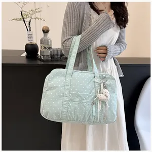 Polka dot travel tote bag in light green carried by a model closeup detail
