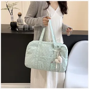 Detail shot of a light green polka dot Boston bag carried by a model in a casual outfit
