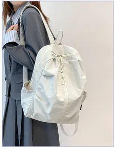 Vue détaillée d'un grand sac à dos de voyage en nylon blanc imperméable porté par un modèle.