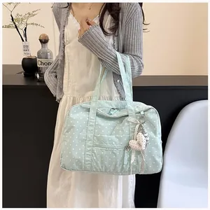 Detail view of a light blue polka dot Boston bag with a cute heart charm for travel.