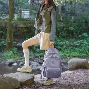 Lifestyle shot of a woman with a light purple outdoor travel backpack by a stream.