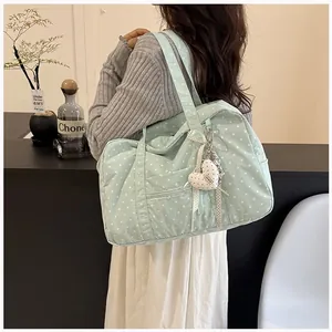 Close-up of a light green polka dot Boston bag worn by a model