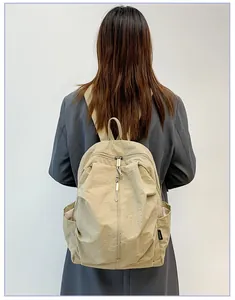Vue de dos d'une femme en blazer gris portant un sac à dos de voyage en nylon beige imperméable