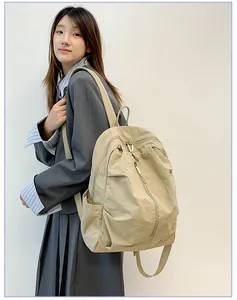 Détail d'un sac à dos en nylon imperméable beige léger porté par un mannequin
