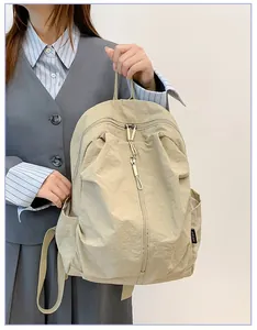 Gros plan d'un sac à dos décontracté en nylon beige tenu par un mannequin
