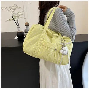 Close-up of a yellow polka dot Boston bag with a cute heart charm worn by a model.