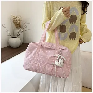 Close-up detail of a pink polka dot Boston bag with a sweet heart charm attachment