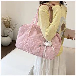 Detailed view of a pink polka dot Boston bag with a heart charm accessory.