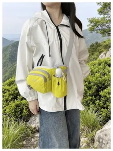A model wearing a bright green e-commerce crossbody bag in a mountain outdoor scene.