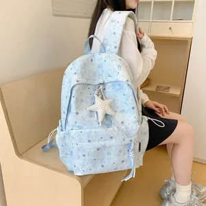 Close-up detail of a light blue star pattern backpack with a plush star charm.