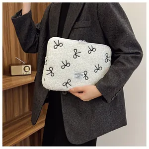 Witte pluche laptophoes met geborduurde zwarte strikjes en dubbele ritssluiting.