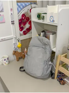 Detail view of a lightweight grey minimalist backpack in a cozy student room setting