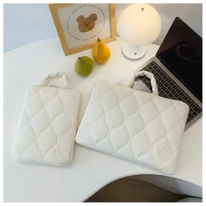 Vue détaillée de deux housses matelassées blanches pour ordinateur et tablette sur bureau