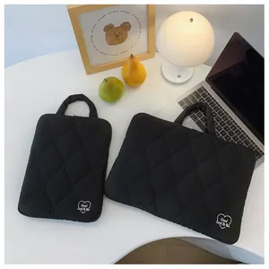 Ensemble de housses d'ordinateur matelassées noires avec motif cœur sur un bureau chic.